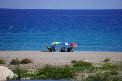 Blue sky, blue sea and 3 coloured beach umbrellas.