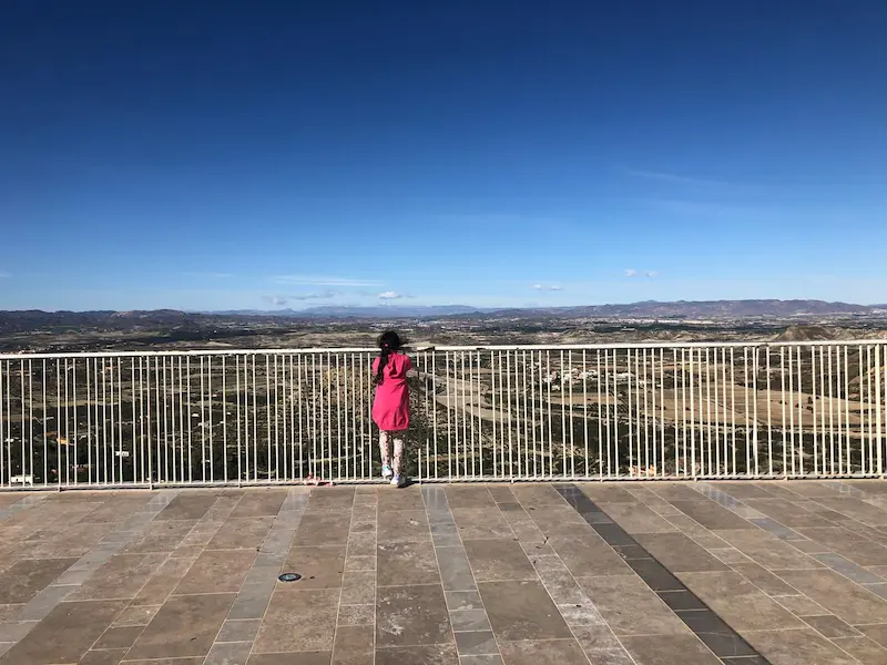 Viewing Point at Mojacar Pueblo - showing a girl in pinking looking over the railings at the landscape beyond.